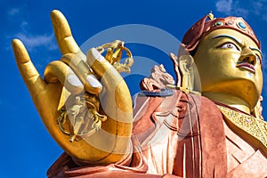 Close up at the right golden hand with mace and head of Guru Rinpoche statue, the patron saint of Sikkim in Guru Rinpoche Temple.