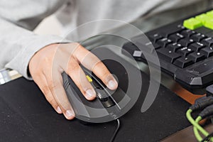 Close up on right hand for clicking over mouse by gamer kid (Selective focus on hand)