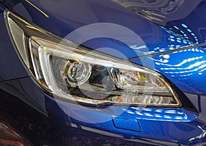 Close up of right headlight of the blue sport car.