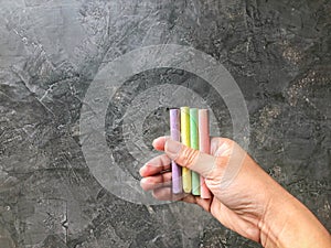 Close up right people hand hold colorful chalk for writing with loft cement background