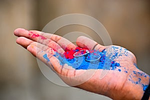 Close up of ring jewelry on human hand with vibrant holi multi colors powder. Selective focus on friendship ring. Happy festival