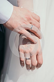 Close-up of the ring newlyweds. The groom gently touches the bride& x27;s hand. Husband and wife hold hands. Vertical photo