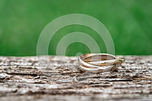Close-up of a ring with three rings on wooden background. Wedding jewelry in gold, white gold and rose gold. macro shot with