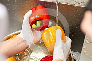 Close up rinsing two bell peppers.
