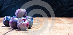 Close-up of ripe home plums on a wooden background in the garden. natural healthy vegan food