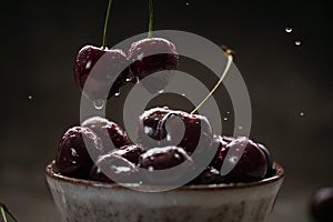 Close up of ripe juicy sweet cherries with water drops in a ceramic bowl