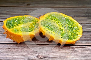 Close-up of a ripe Kiwano or Horned Melon fruit, sliced length-wise on wooden table top