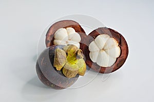 Close-up of a ripe mangosteen fruit & 2 open halves on white background