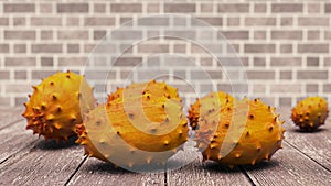 A close-up of a ripe orange horned melon fruits on the wooden table. Brick wall background