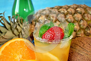 Close-up of a ripe strawberry and mint in the glass with orange drink