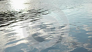 Close up of ripples on the surface of the river with clouds reflection in the water. Stock. Flow of dark water in calm