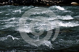 Close-up of a river flow on the rocks. Clean bubbling transparent blue water in a mountain river. Selective focus