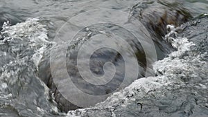 Close up of river stream flowing down over the grey stones