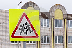 Close-up road sign caution children on the background of the school.