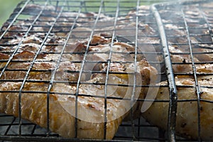 close-up: roast porkmeat inside grill on fire with smoke
