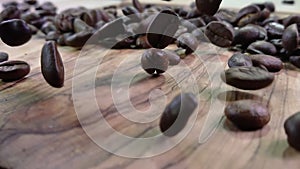 Close-up of roasted arabica coffee beans falling down on the wooden texture
