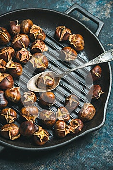 Close-up of roasted chestnuts and spoon in grilling pan