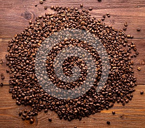 Close-up roasted coffee beans on brown wooden background, top view, copy space