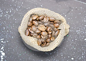Close-up of Roasted coffee beans in a burlap bag on a dark background, top View