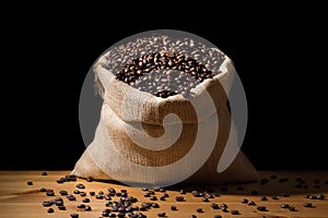 Close up roasted coffee beans in a burlap hessian sack on a wooden surface and isolated in black. Coffee beans scattered.