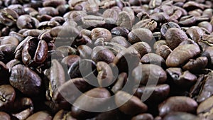 Close-up of roasted coffee beans falling on the brown coffee texture