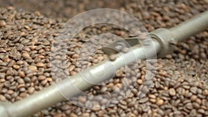 Close-up of roasted coffee beans mixing on spinning mechanism