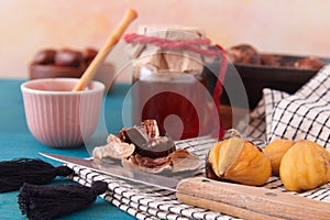 Close up of roasted edible chestnuts with honey on blue table