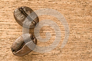 close-up roasted two coffee beans with dark brown color on the wooden table background