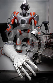 Close up of robot hand on table with another robot and details at background