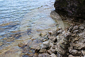 A close up of the rocky shoreline of Lake Michigan with water lapping over the rocks in the summer in Cave Point County Park