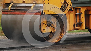 Close up of roller levels the newly laid asphalt. Construction machinery performs energy intensive heavy work on project