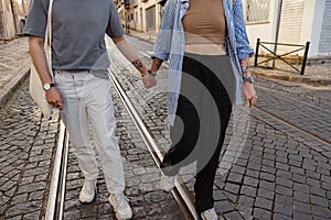 Close up of romantic couple in love holding hands while walking on old city street