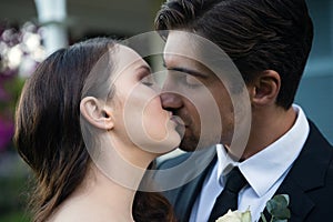 Close up of romantic newlywed couple kissing in park