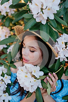 Close up romantic portrait of beautiful elegant woman in straw hat in blossom spring trees outdoor