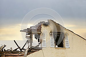 Close up of a roof top of a stucco home charred and burned.