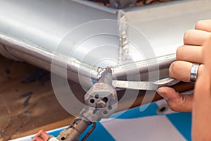 Close-up of a roofer applying weld into the gutter parts to assemble it.