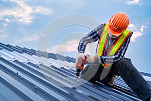 Close up Roofer worker safety wear using air or pneumatic nail gun and installing on new roof metal sheet, Roof concept of