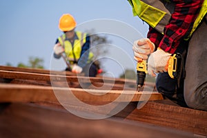 Close up roofer working on roof structure of building on construction site, Roofer using air or pneumatic nail gun and installing