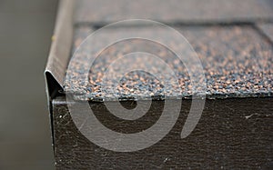 A close-up of a roofing asphalt shingle with a focus on the thickness of asphalt roofing material