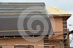 A close-up on a roofing construction with asphalt roof shingles installation on the waterproof underlayment and uncovered roof