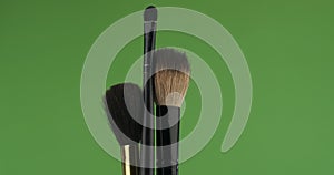 Close-up, rotation, set of a powder brush and rouge, on a green screen.