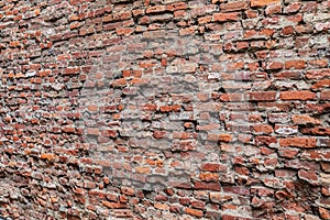 Close up of a rough brick wall with bricks on the left farther away than the right