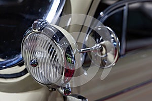 Close-up of the round headlamps of a beige classic car.