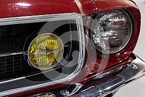 Close-up of the round headlamps of a red american classic car.