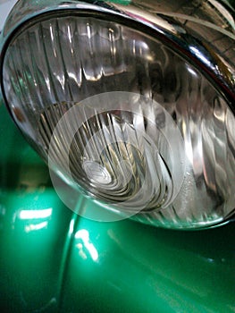 Close-up of a round headlight of a retro car in green