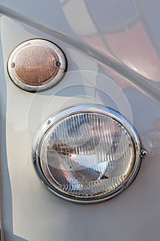 Close-up round headlight of shiny grey vintage retro car.