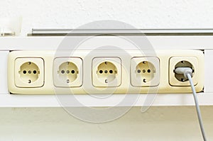 Close-up of a row of electrical outlets with a plug inserted