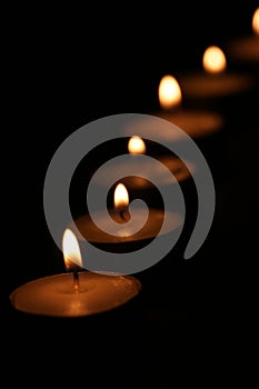 Close-up of a row of tealight candles burning in a dark room