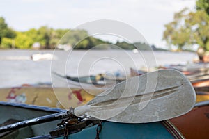 close-up of rowing paddle and out of focus canoes in the background