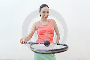 Close-up of a rubber hollow ball on the new squash racket of a fit woman